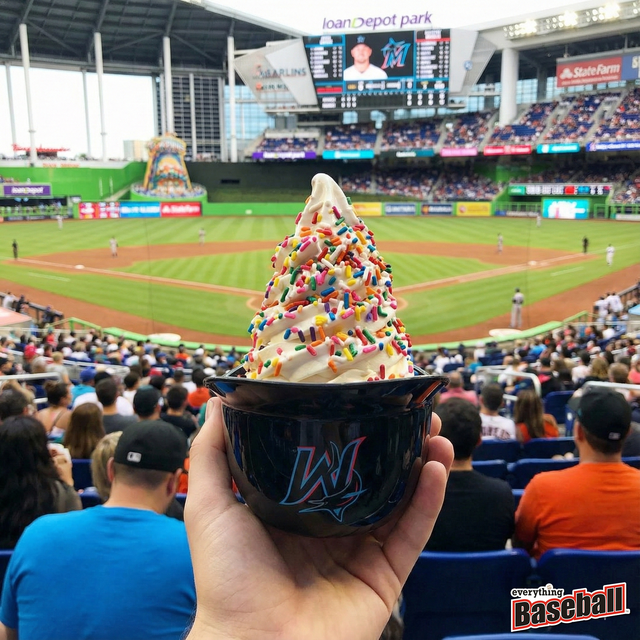 Colorful ice cream sundae helmet held up at a Miami Marlins baseball game with stadium and spectators in the background.