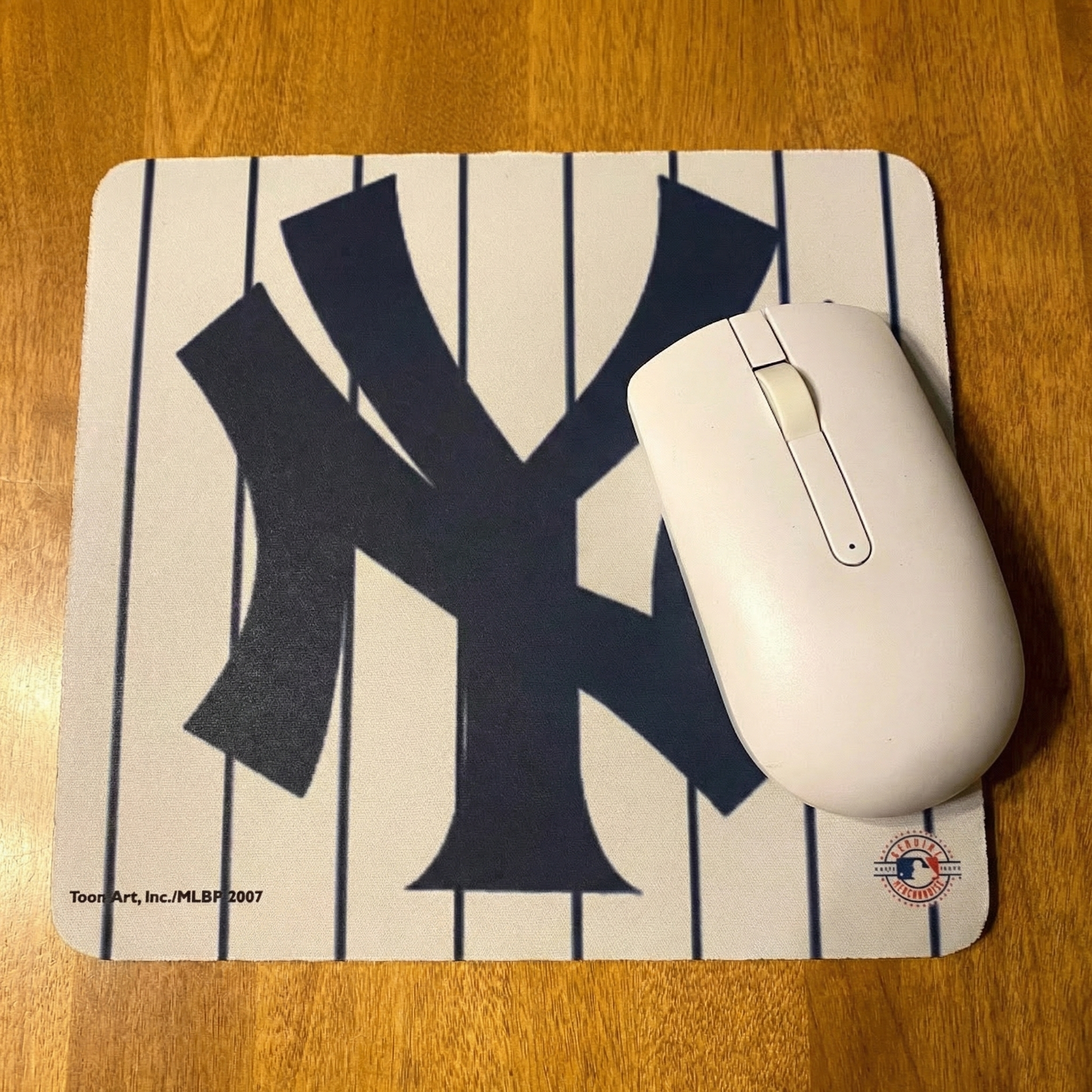 Mouse pad with New York Yankees pinstripes logo and a white mouse on a wooden surface