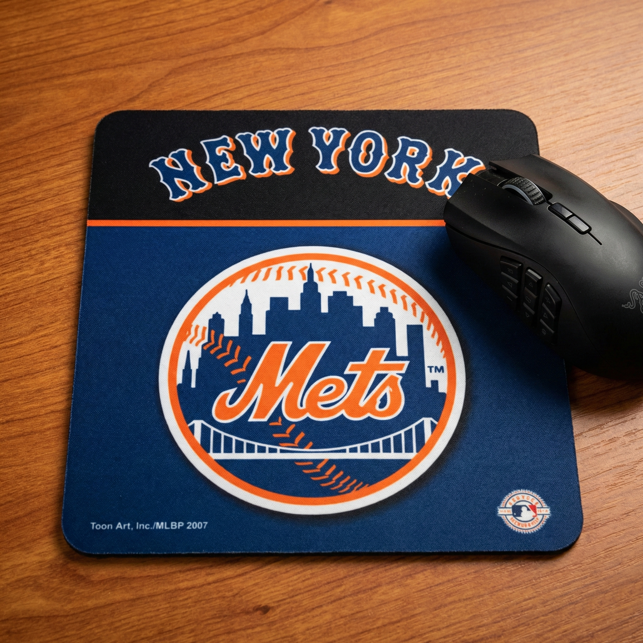 New York Mets mouse pad with a black gaming mouse on a wooden surface