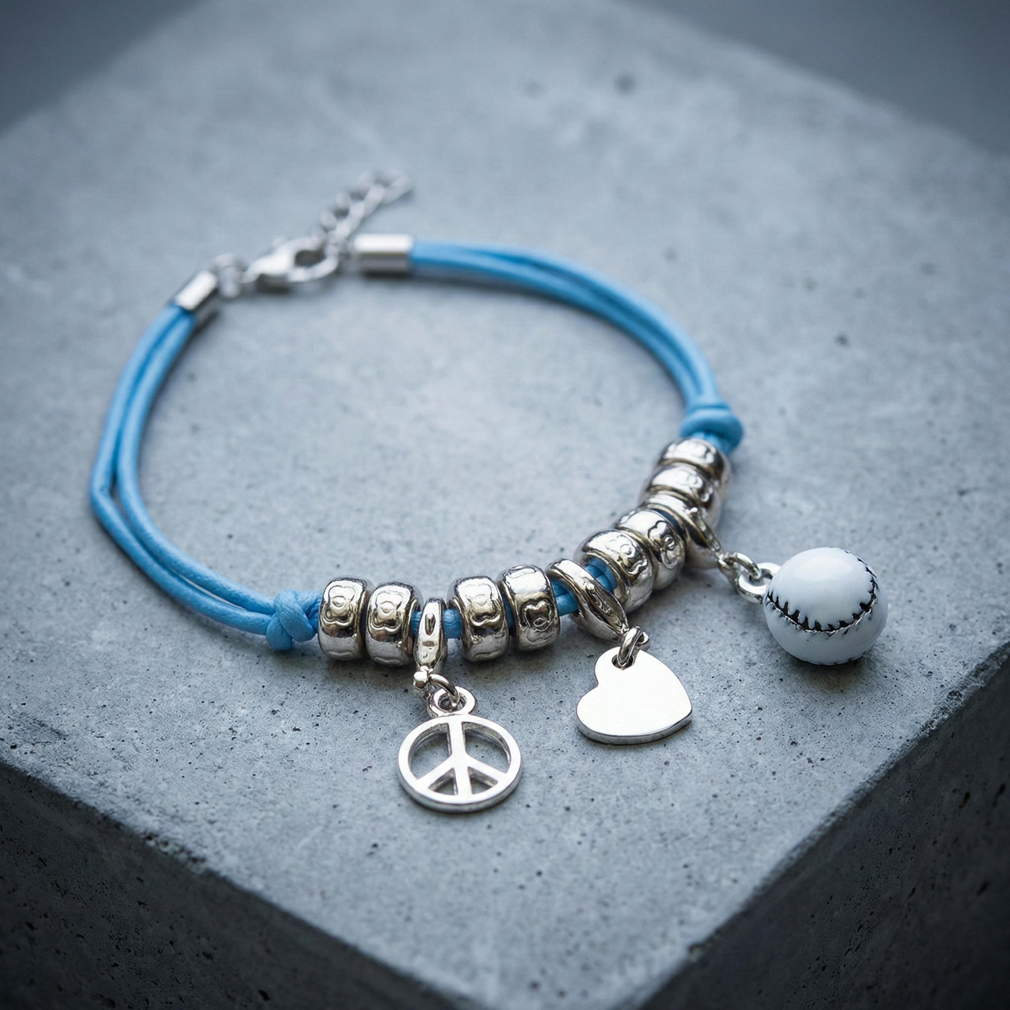 Peace Love Baseball 3-Charm Bracelet on concrete surface.