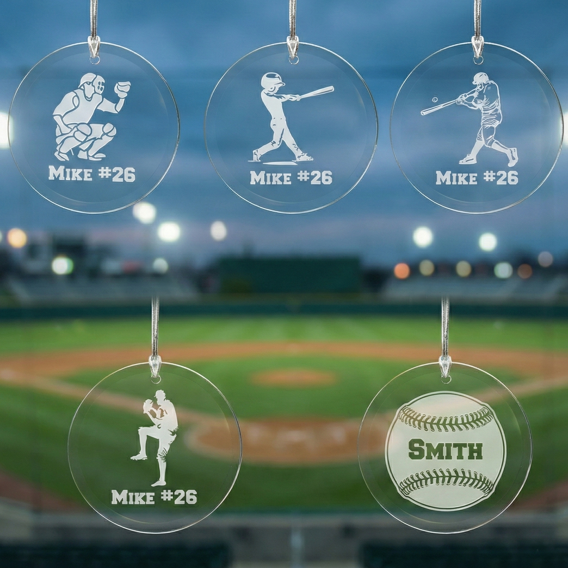 Five personalized baseball-themed Christmas glass ornaments with player illustrations and names against a blurred baseball field background.