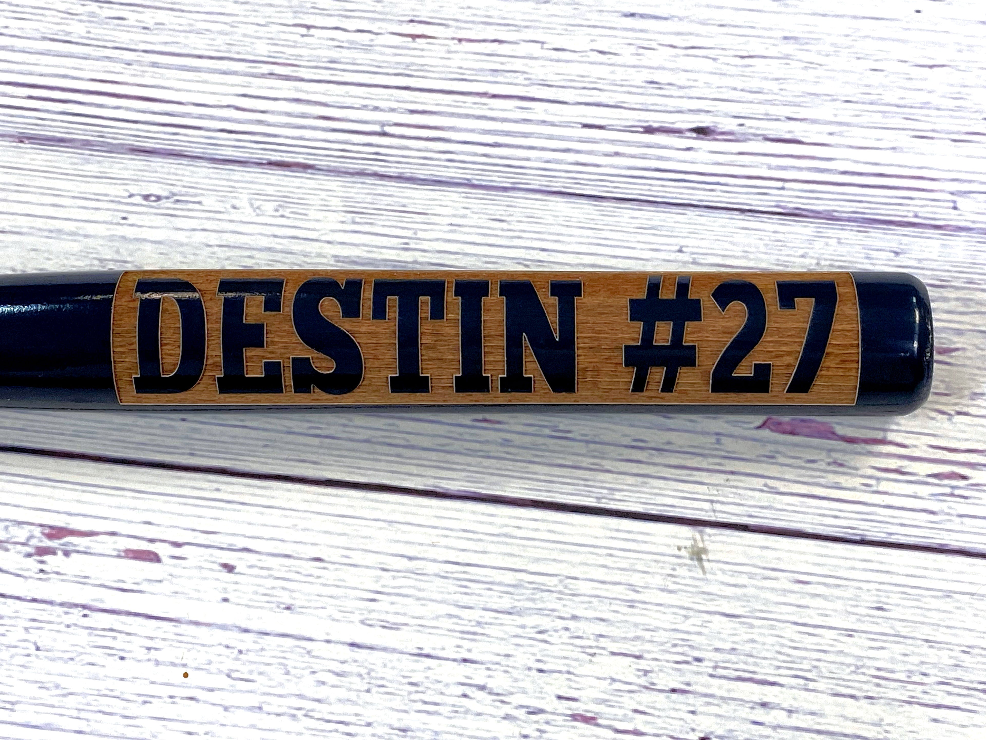 Wooden baseball bat with 'DESTIN #27' engraving in barrel