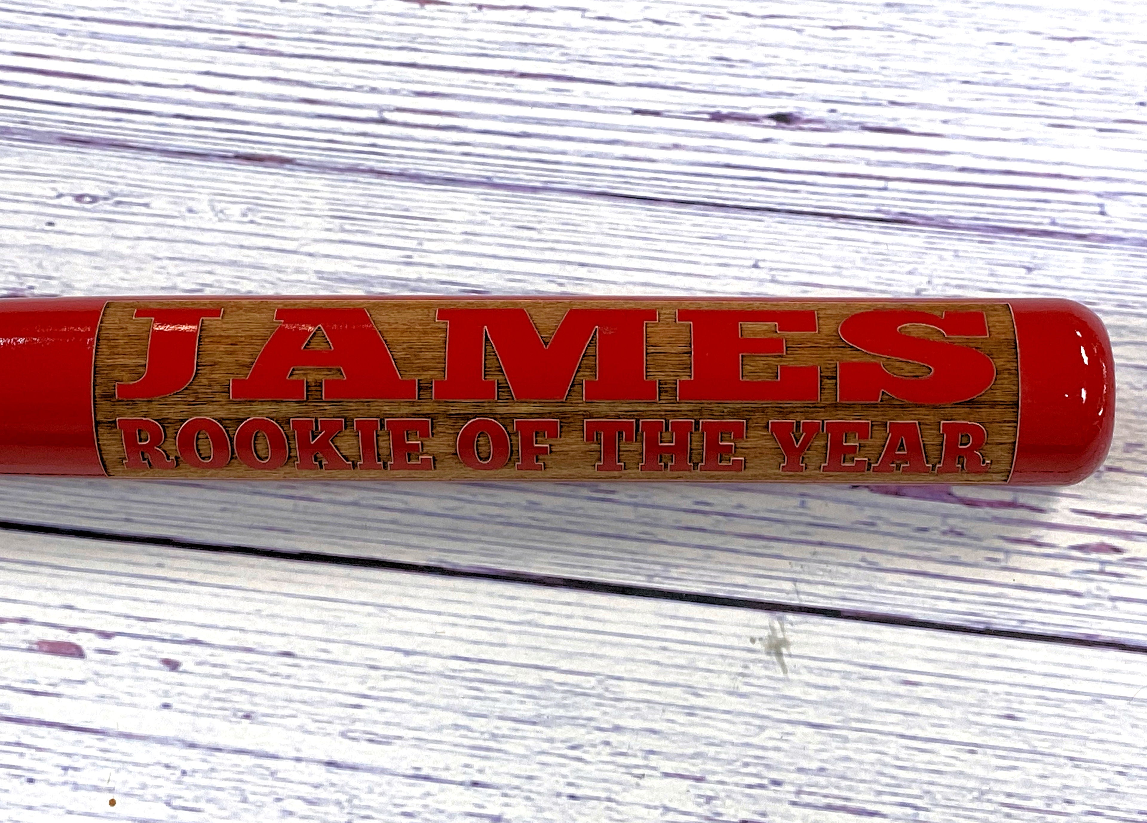 Red and wooden baseball bat with engraved text on a white background