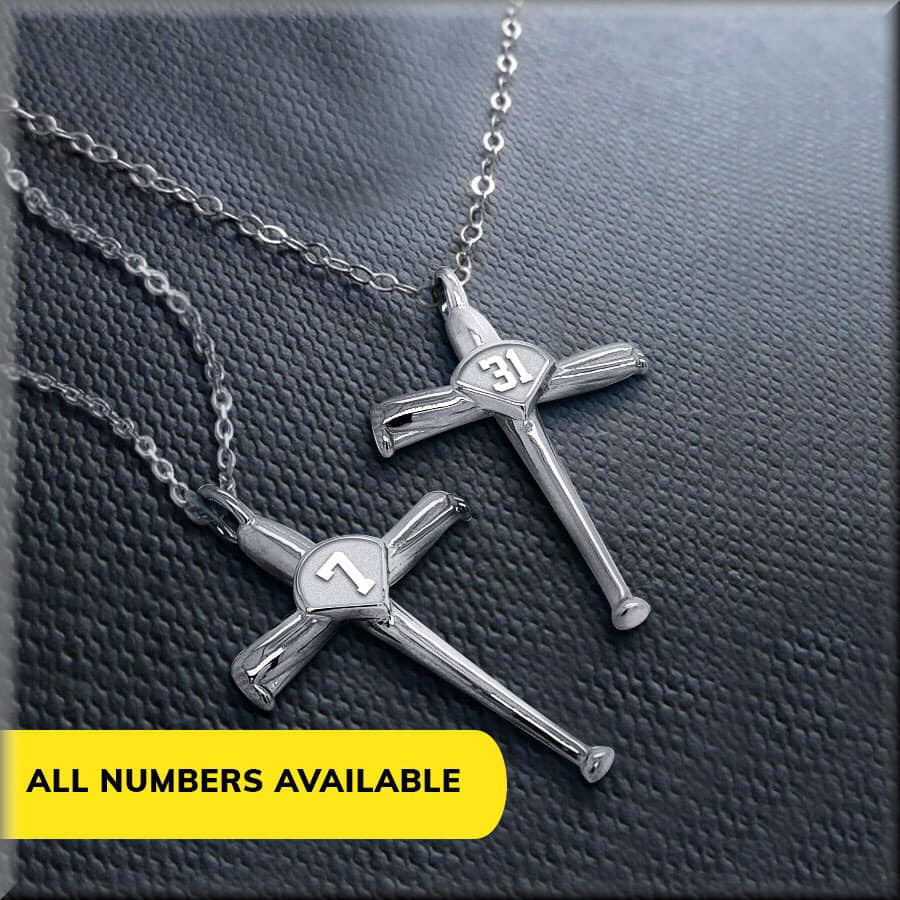 Two silver baseball cross necklaces with engraved numbers on a textured surface