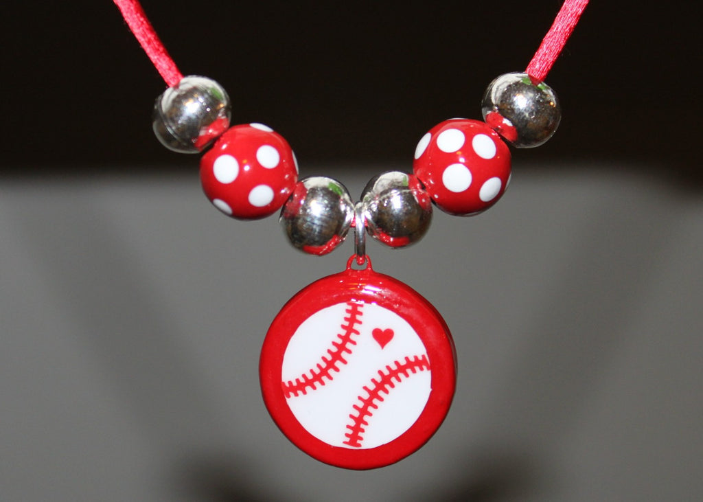 Necklace with red polka dot beads and a baseball charm on a dark background