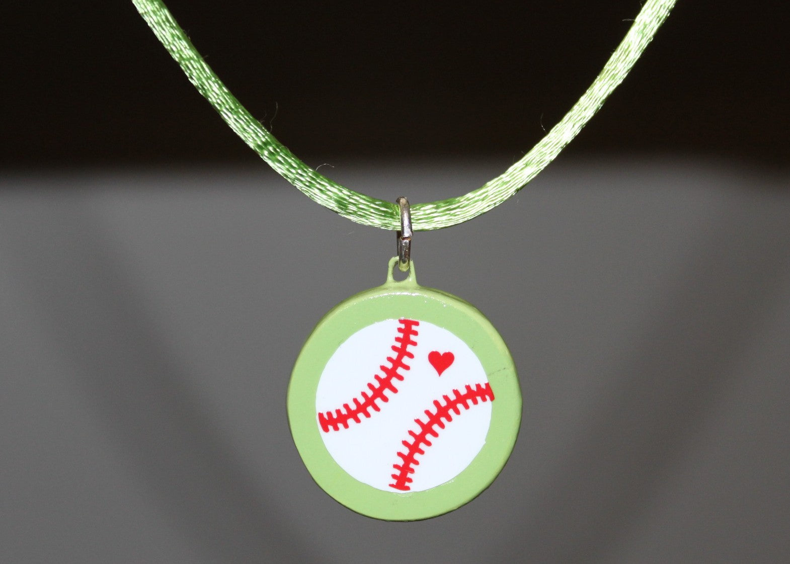 Lime green necklace with a pendant featuring a baseball design on a dark background