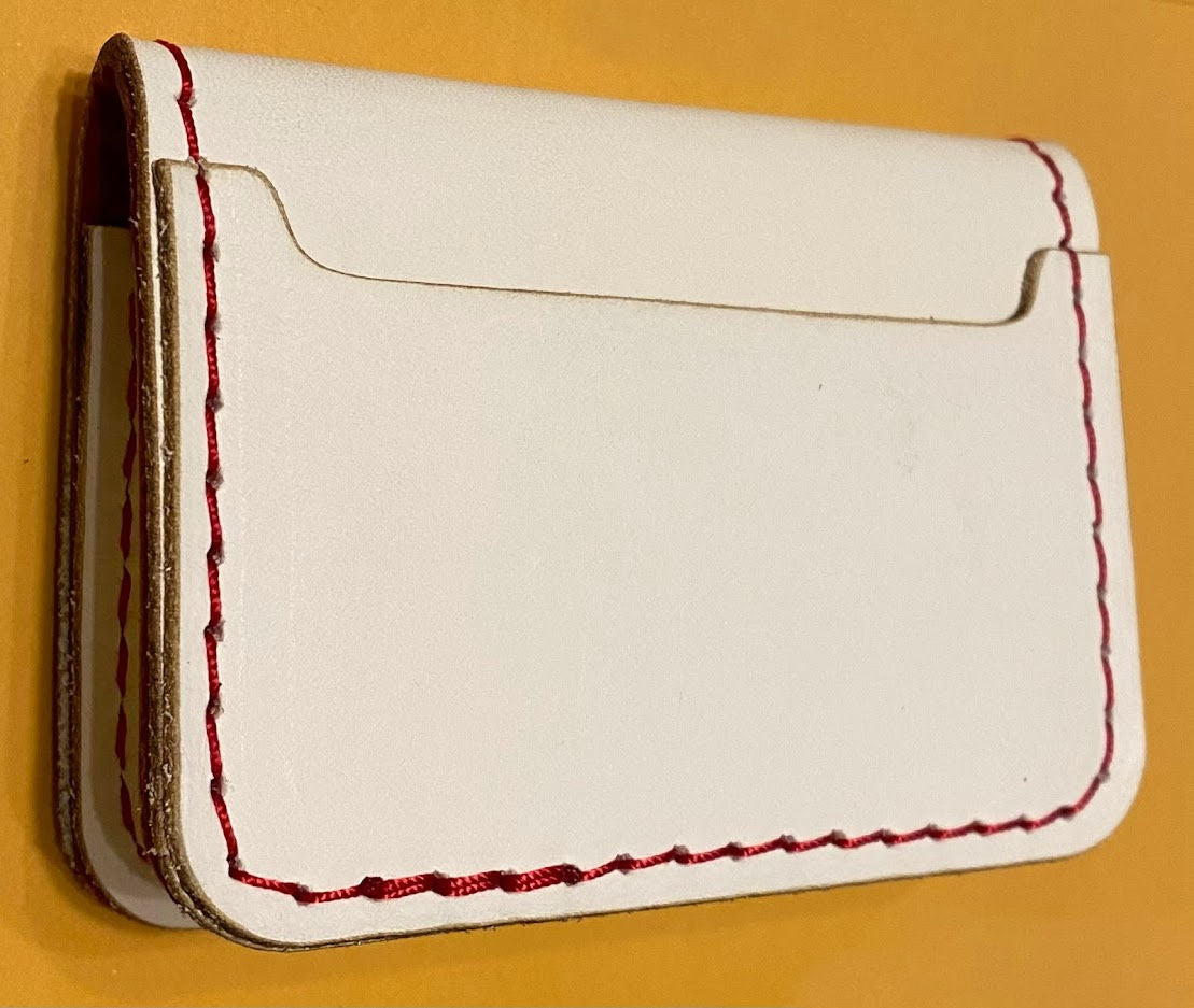 White cardholder with red stitching on a yellow background