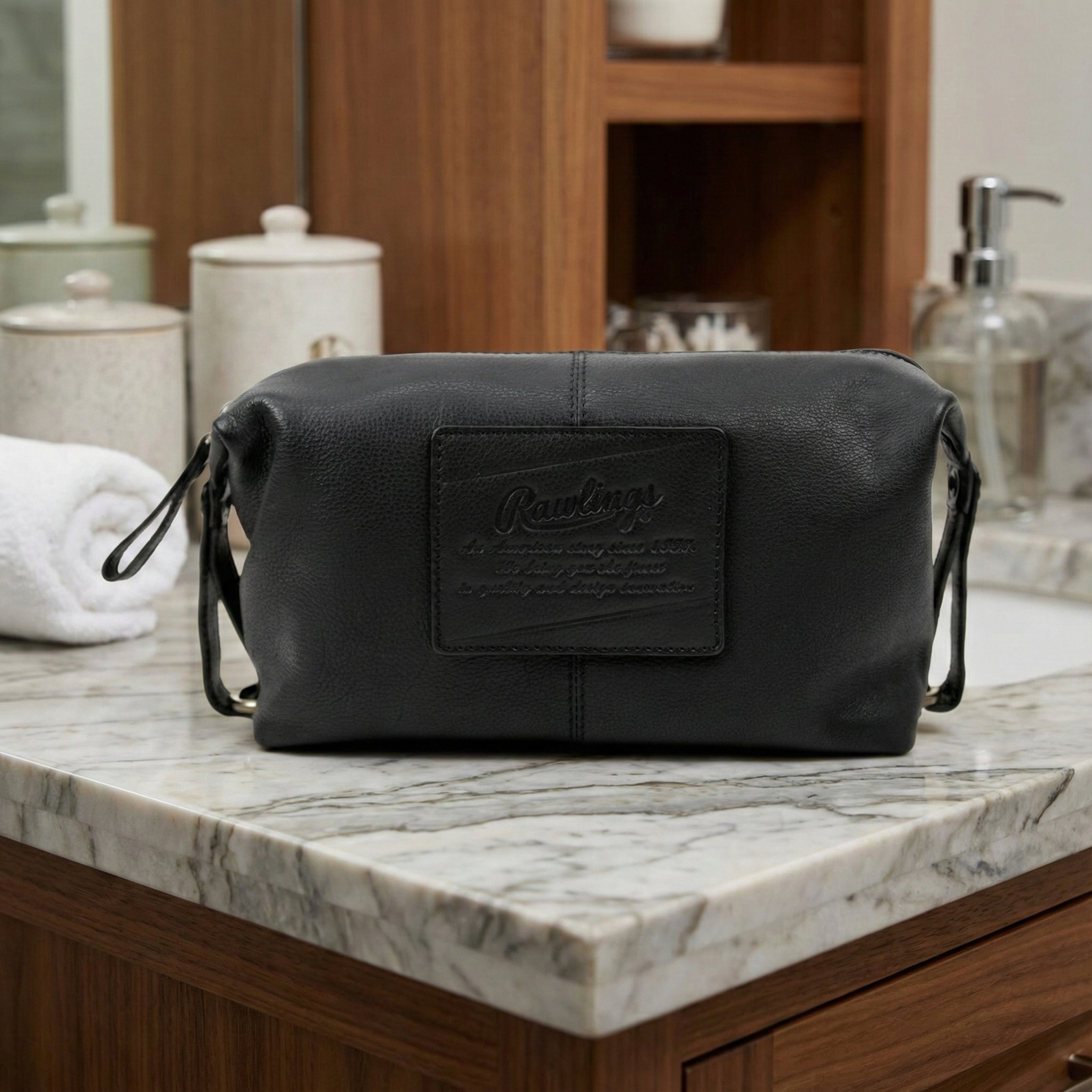Rawlings black leather toiletry bag with brand logo on a marble countertop in a bathroom setting