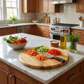 Kitchen counter with round wooden baseball cutting board, vegetables, and kitchen appliances