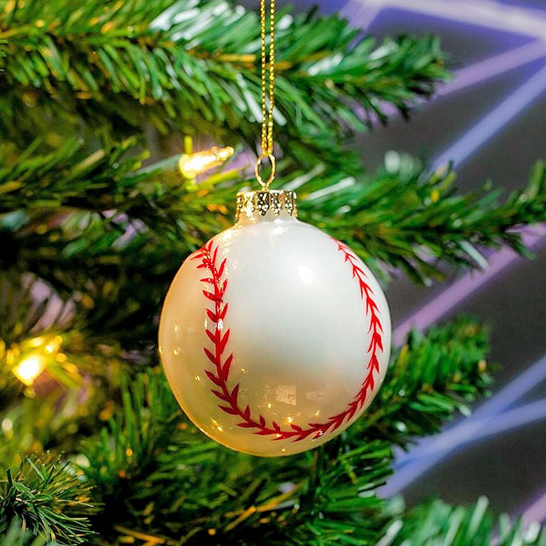 Baseball-shaped Christmas tree ornament on a tree with lights