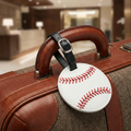 Brown suitcase with a baseball-themed luggage tag featuring red stitching.