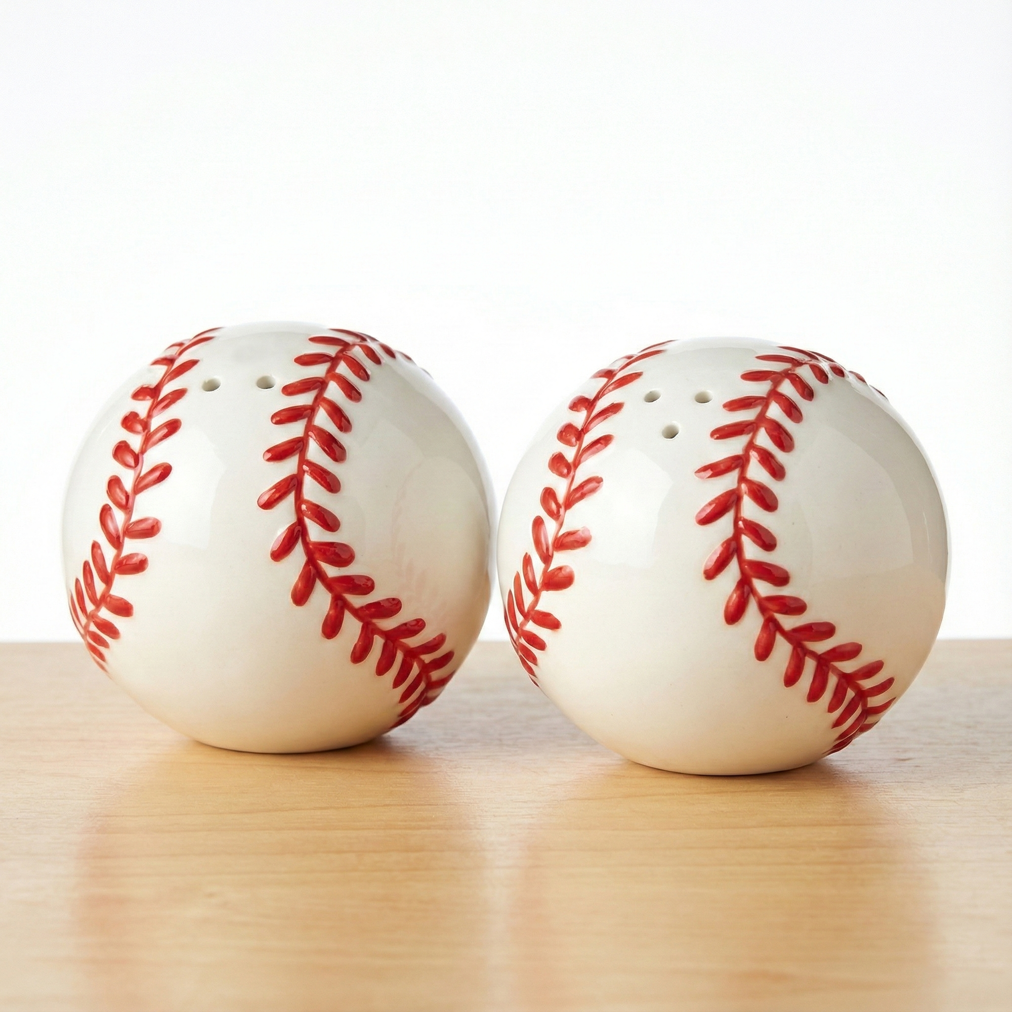 Two baseball-themed salt and pepper shakers on a wooden surface with a white background