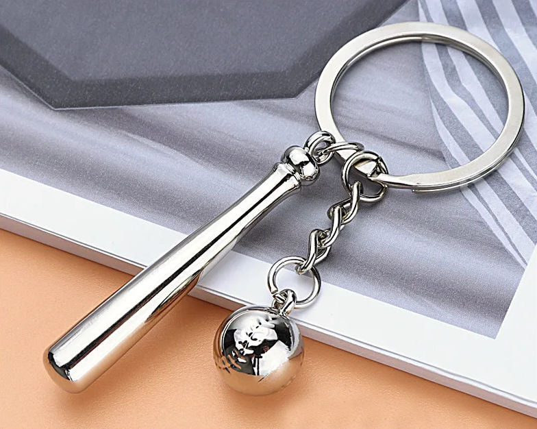 Silver keychain with a bat and baseball design on a textured surface