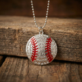 Baseball-shaped pendant with red stitching on a silver chain, placed on wooden surface