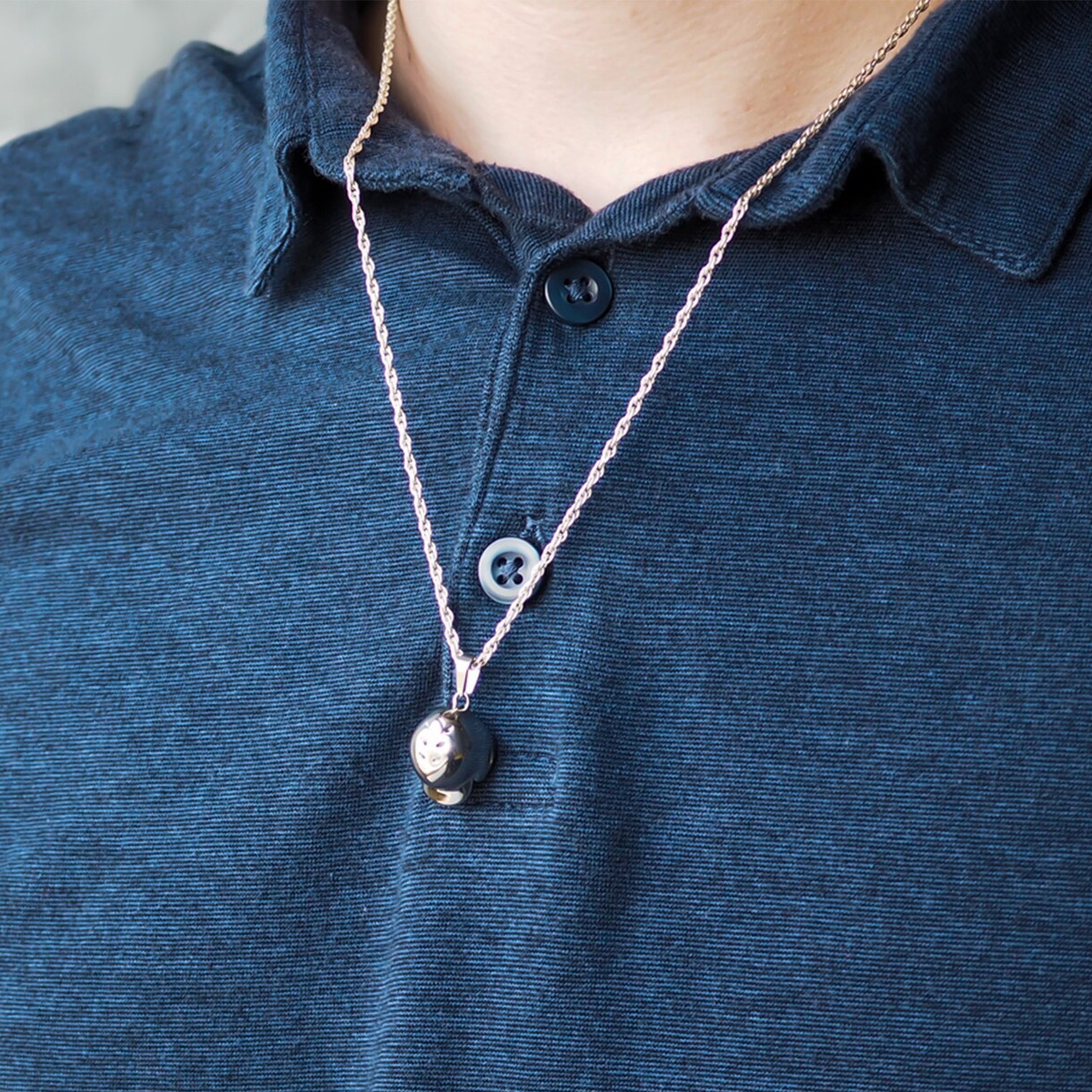 Necklace with a baseball helmet 3d pendant on a person wearing a blue polo shirt.