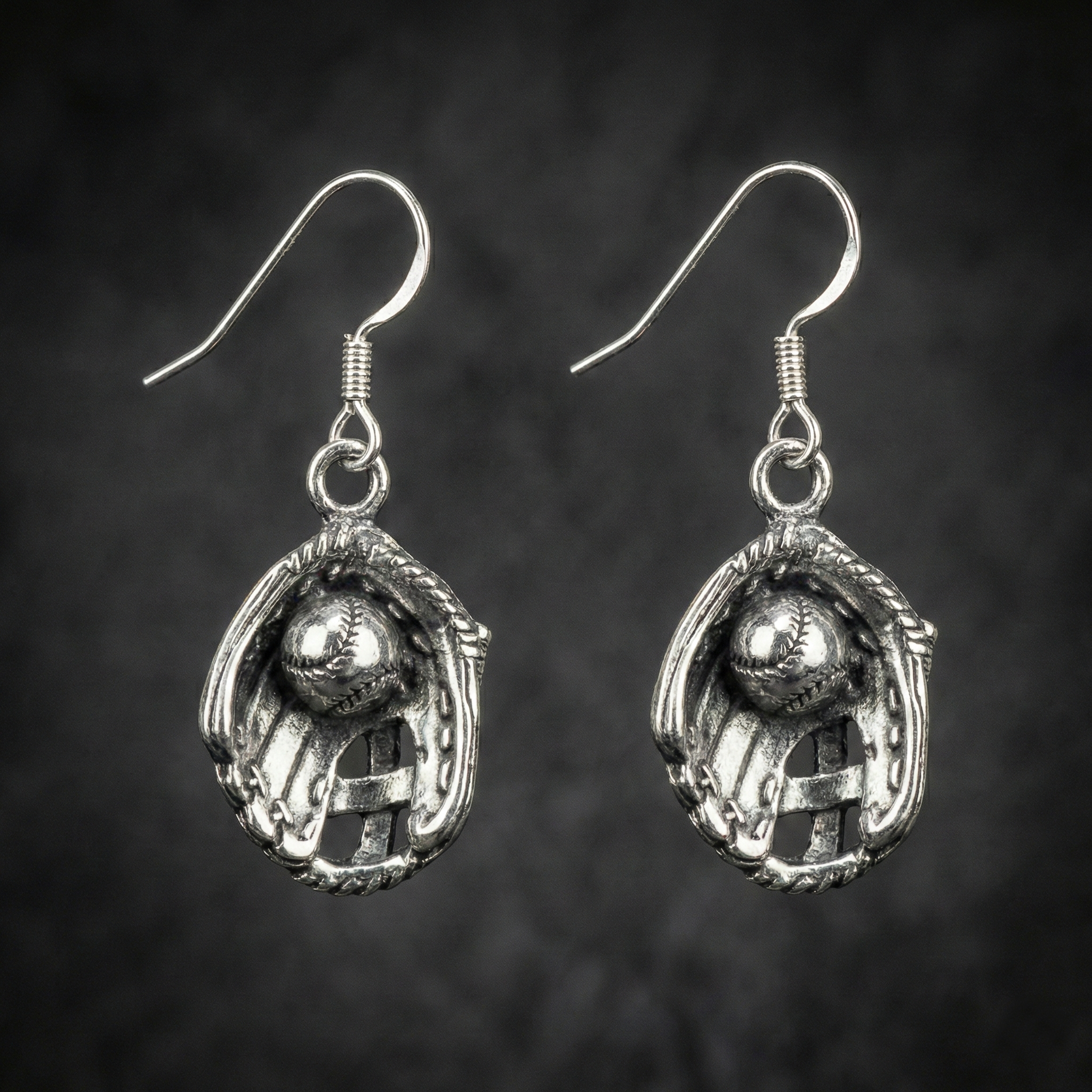 sterling silver baseball glove dangle hook earrings on cool black background.