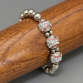 Silver beaded baseball bracelet with red accents on a wooden surface