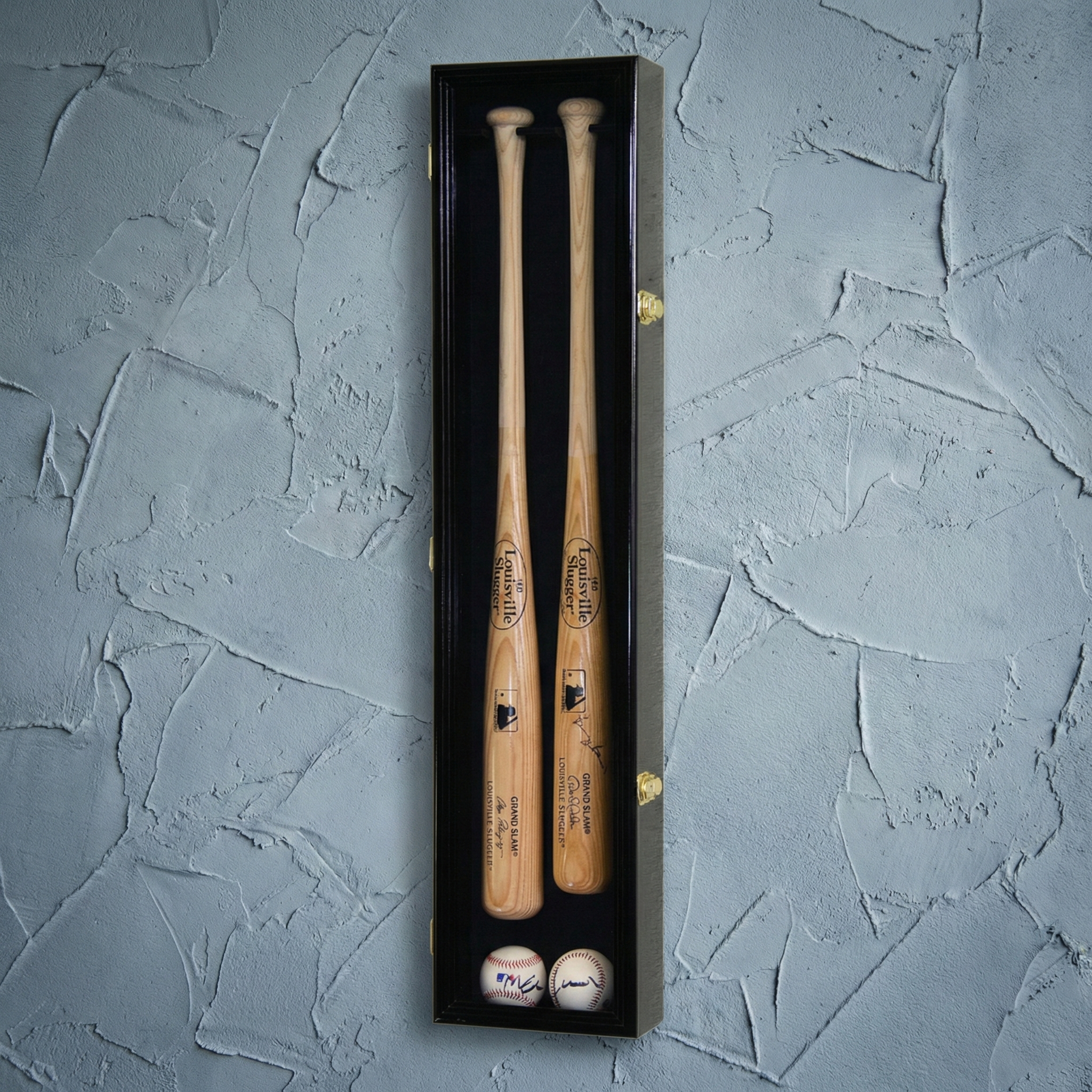 Two wooden baseball bats and two balls in a black box on a textured gray background