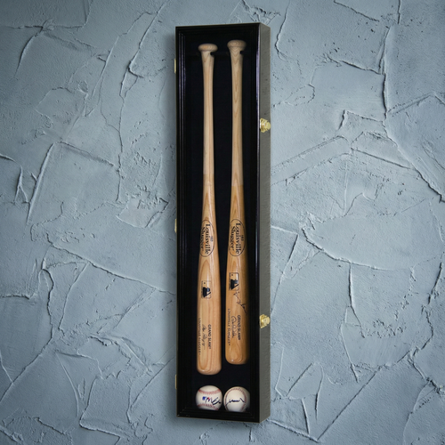 Two wooden baseball bats and two balls in a black box on a textured gray background