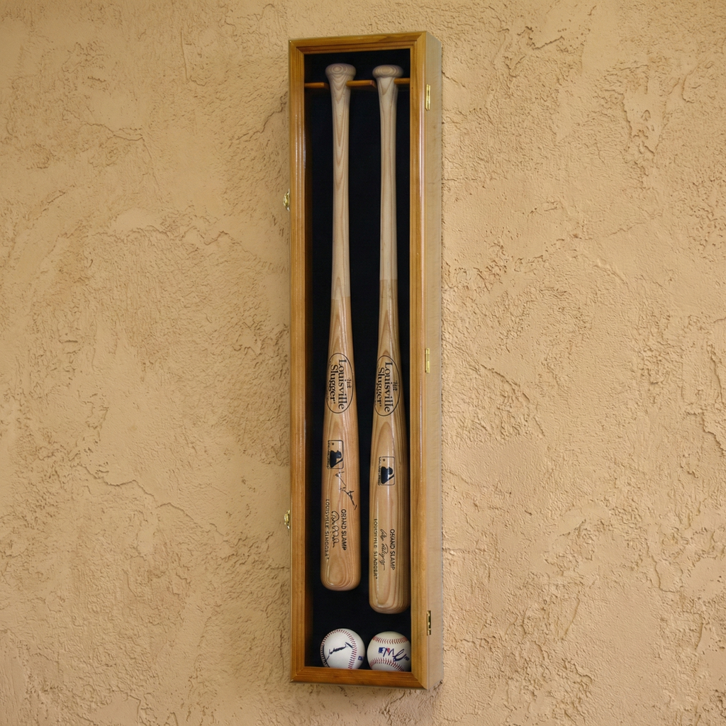 Two baseball bats and two balls in a wooden display case against a beige wall.