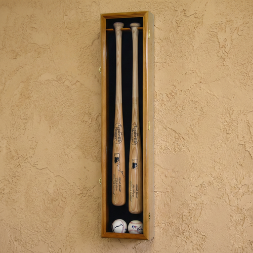Two baseball bats and two balls in a wooden display case against a beige wall.