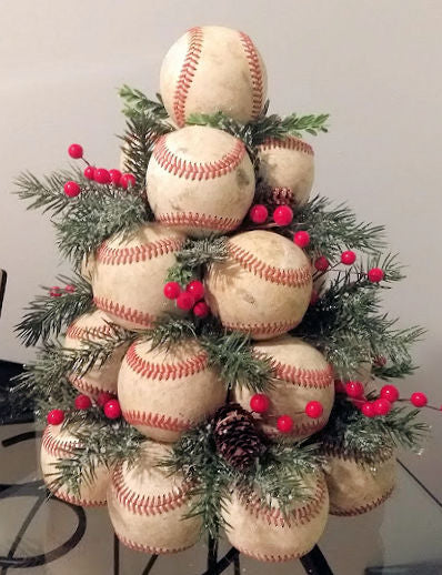 Decorative Christmas tree made of real used leather baseballs with greenery and red berries on a plain background