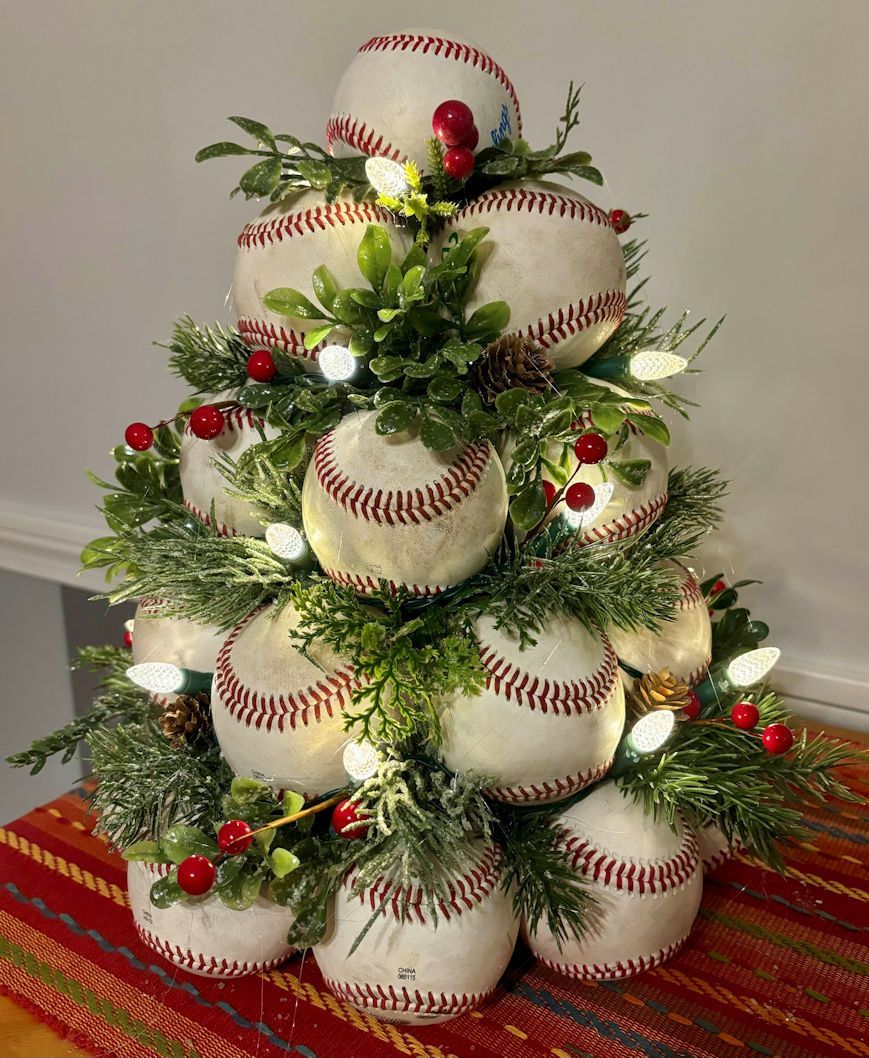 Christmas tree made of used leather baseballs with lights and decorations on a striped tablecloth.