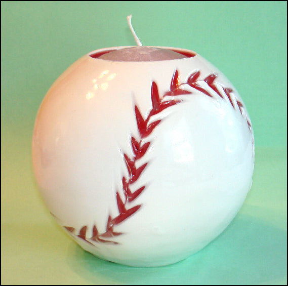 Baseball-shaped candle with red stitching detail on a green background