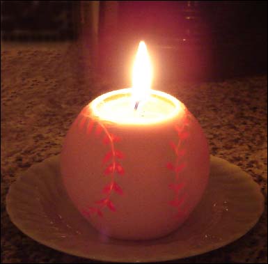 Baseball shaped candle glowing on a textured surface