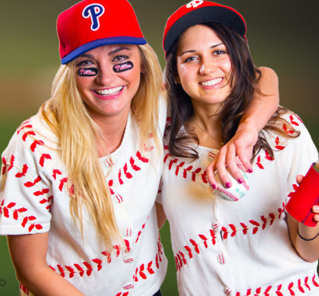Two women wearing baseball-themed shirts and hats, posing together.