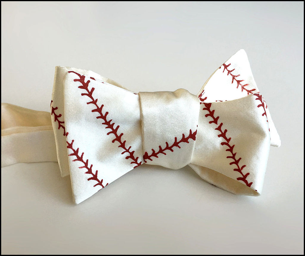 Baseball-themed bow tie with red stitching on a light gray background