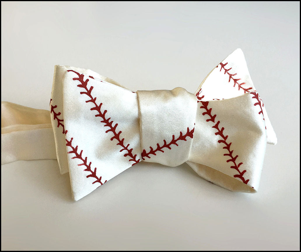 Baseball-themed bow tie with red stitching on a light gray background