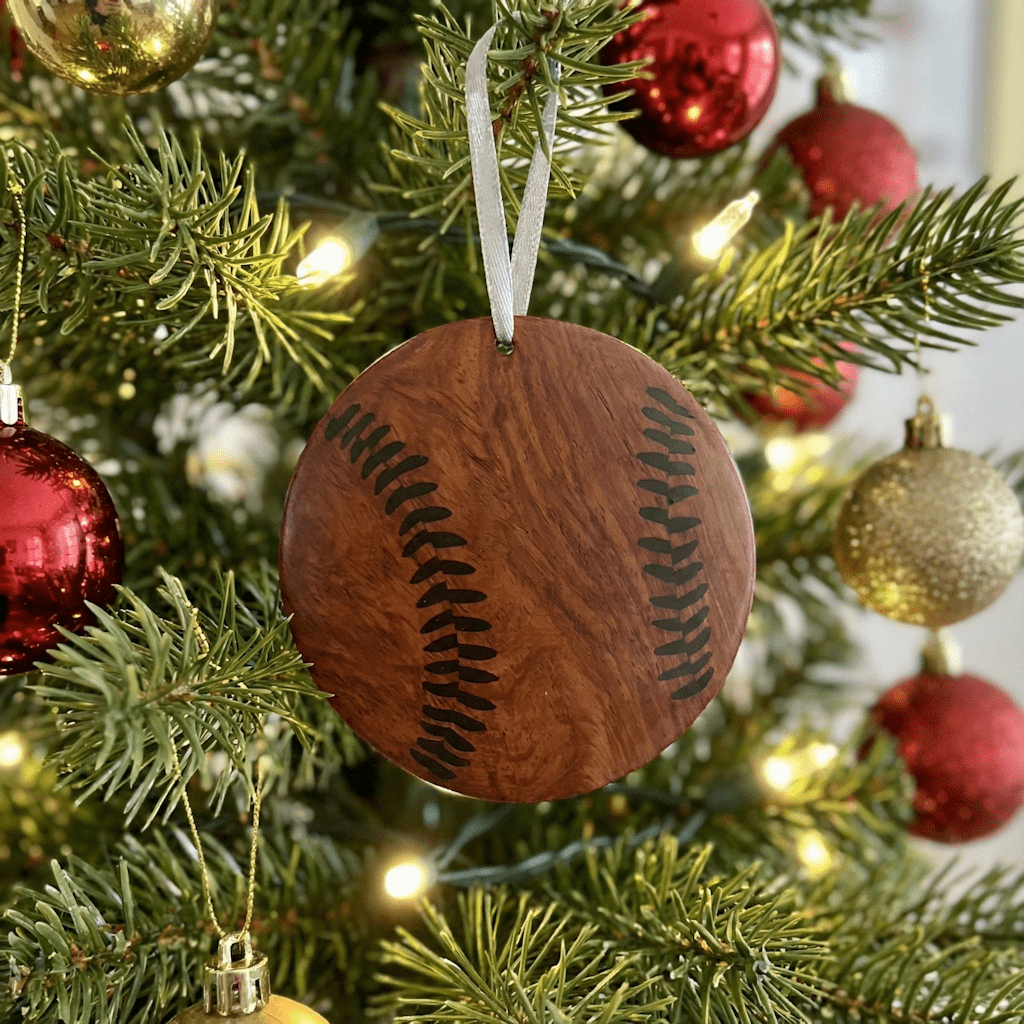 Wooden baseball ornament on a Christmas tree with red and gold decorations.